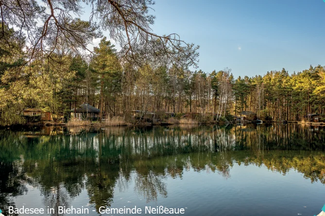 Badesee in Biehain mit Spiegelungen der Bäume im Wasser